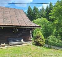 A cottage in Zákopčie surrounded by forests, with a bench and wooden details.