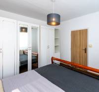Bedroom in a 2-room apartment with a bed, wardrobes, and a mirror.