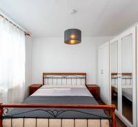 A simply furnished bedroom with a wardrobe and a large window in a 2-room apartment.