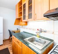 A kitchen in a 2-room apartment with light wooden furniture and appliances.
