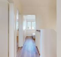 A hallway with a wooden floor leading to the rooms in a family house.