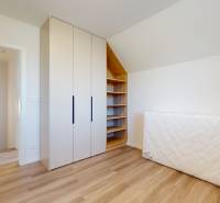A room in a family house with a wooden floor, a wardrobe, and a mattress by the wall.