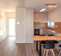 A kitchen with a dining table in a family house, with wooden paneling and a built-in oven.