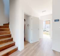 A staircase with wooden steps next to a white wall in a family house.