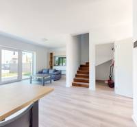 Interior of a family house with a living room, sofa, stairs, and large windows.