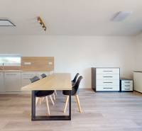 A kitchen in a family house with light furnishings, a dining table, and black chairs.