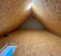 Attic with a wooden structure and a light fixture in the attic space of a family house.
