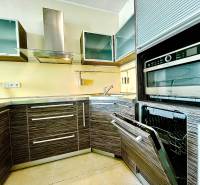 A kitchen in a 2-room apartment with stainless steel appliances and wooden cabinets.