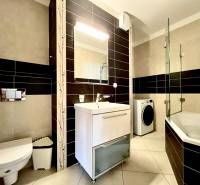 Bathroom in a 2-room apartment with a bathtub, toilet, and washing machine.