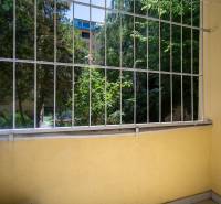 A small balcony with a view of greenery and wooden elements in a 3-room apartment.