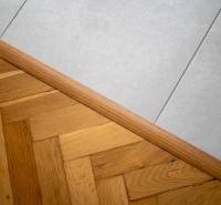 Transition between wooden flooring and white tiles in a three-room apartment.