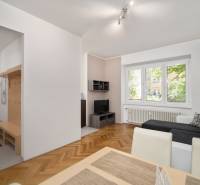 Living room with a sofa, dining table, and hallway in a 3-bedroom apartment.