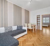 Living room with orange wooden furniture, a sofa, and a dining table in a three-room apartment.