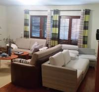 Living room with comfortable sofas, wooden furniture, and curtains in a family house.