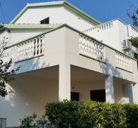 A family house in Vrsi with a white balcony and greenery in the surroundings.