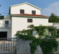 A family house in Vrsi with a white facade and a terrace surrounded by greenery.