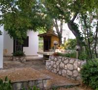 A family house in Vrsi surrounded by trees and stone elements.