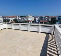 The terrace of a family house in Vrsi with a view of the surrounding buildings and the blue sky.
