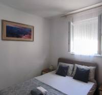 A bedroom in a family house with a bed, a painting, and an open window.