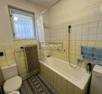 Bathroom in a family house with a bathtub, radiator, and window, decorated with tiles.