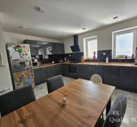 A kitchen in a family house with dark cabinets, a wooden table, and a refrigerator full of magnets.