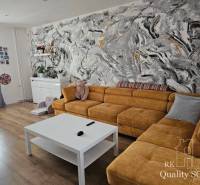 Living room in a family house with a yellow sofa and an abstract wall with colorful strokes.