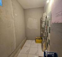 Interior of a family house with tiles, a bucket, a ladder, and construction materials.
