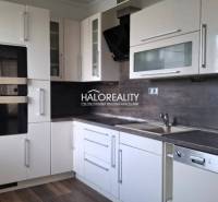 A kitchen in a 2-room apartment with white cabinets and a dark countertop.