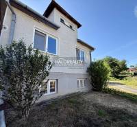 A family house in Padarovce with two floors near a garden and a road, surrounded by greenery.