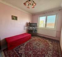 A room in a family house with a carpet, a sofa, a window, and a painting on the wall.