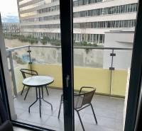 A balcony with furniture in a 2-room apartment overlooking neighboring buildings.