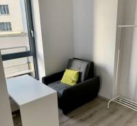 Armchair, table, and stand in a 2-room apartment with a large window and floor.