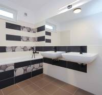 A bathroom in a 3-room apartment with a bathtub, two sinks, and black-and-white tiles.
