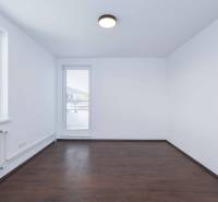 An empty room with a dark floor and a window in a 3-room apartment.