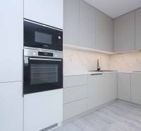A kitchen in a family house with white cabinets, a stove, and marble tiles.