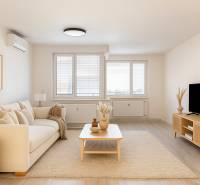 Living room in a 3-room apartment with a beige couch, a table, and a television on a stand.