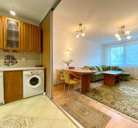 A kitchen with wooden furniture, a living area with a sofa in a 3-room apartment.