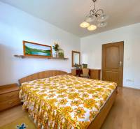 A bedroom in a 3-room apartment, with wooden furniture and a striking floral bedspread.