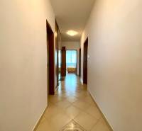 A corridor with a tiled floor in a 3-room apartment, leading to a sunny room.
