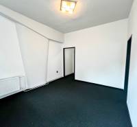Commercial premises with white walls, dark flooring, and a radiator located in the interior.