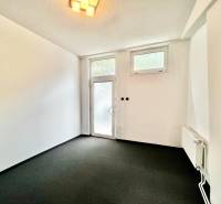 Interior of a commercial space with black carpet, white walls, and glass doors.