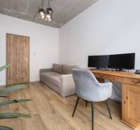 A study in a 4-room apartment with a desk, computers, and a gray chair, wooden floor.