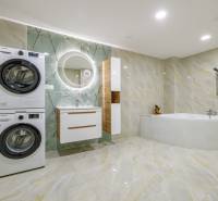 A bathroom in a 4-room apartment with a bathtub, washing machine, dryer, and mirror.