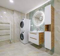 Spacious bathroom with a washing machine, dryer, round mirror, and built-in furniture in a 4-room apartment.