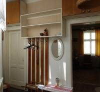 Interior of a family house with coat racks, a mirror, and a window with curtains.