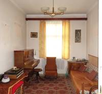 A room in a family house with a piano, brown furniture, and curtains.