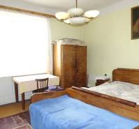 A bedroom in a family house with wooden furniture, a painting, and a chandelier.