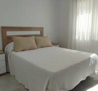Bright bedroom with curtains, a double bed, and a nightstand in a 4-room apartment.