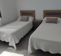 Two single beds with a nightstand and tasteful decorative pillows in a four-room apartment.