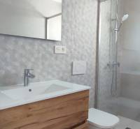 A bathroom in a 4-room apartment with a wooden cabinet, a shower corner, and a mirror.